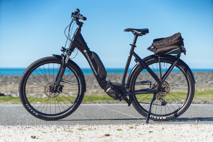 Black electric bike parked on a road with ocean in the background.