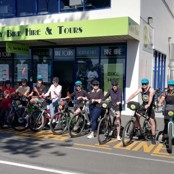 Group of people with bicycles outside Napier City Bike Hire & Tours storefront.
